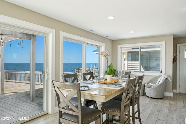 dining area with light wood-style flooring, recessed lighting, baseboards, a water view, and visible vents