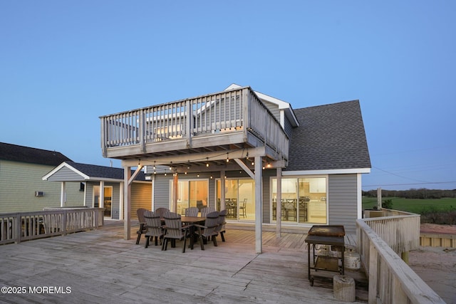 back of house featuring a shingled roof, a deck, and outdoor dining space
