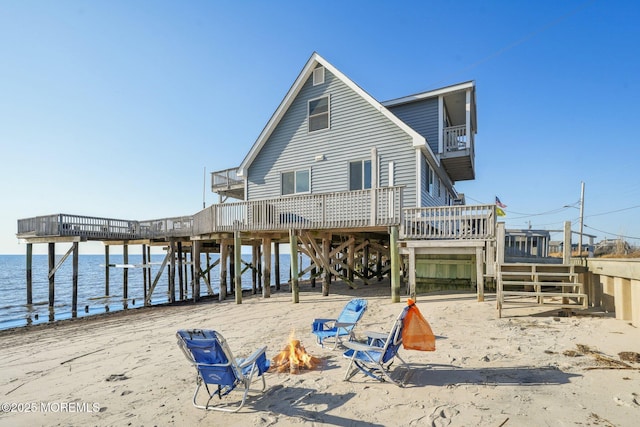 rear view of house with an outdoor fire pit and a deck with water view