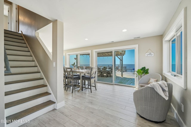 living room with stairs, baseboards, visible vents, and light wood-type flooring