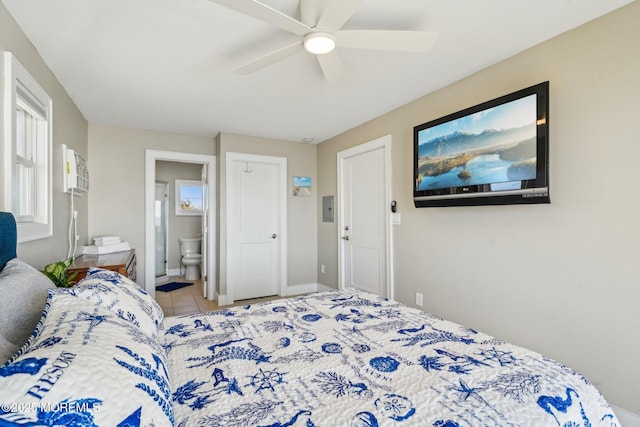 bedroom with baseboards, ceiling fan, tile patterned floors, and ensuite bathroom