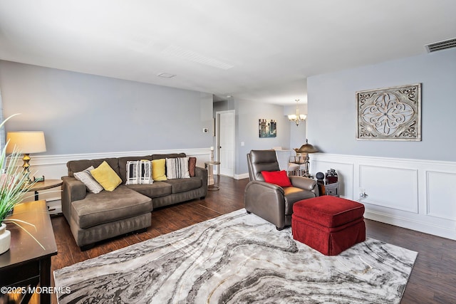 living area with visible vents, wainscoting, wood finished floors, and a chandelier