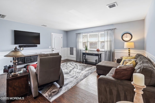 living area featuring dark wood-style flooring, visible vents, and wainscoting
