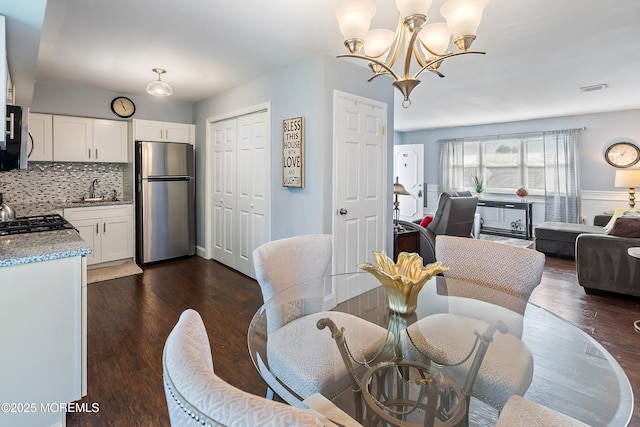 dining space with an inviting chandelier, dark wood-type flooring, and visible vents