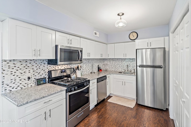 kitchen featuring light stone countertops, white cabinetry, a sink, backsplash, and stainless steel appliances