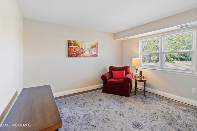 living area with baseboards and visible vents