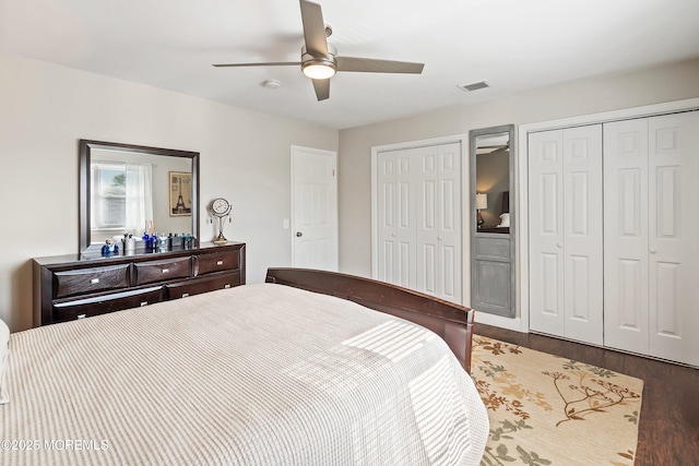 bedroom featuring a ceiling fan, two closets, wood finished floors, and visible vents