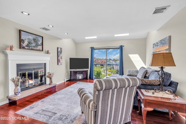 living room featuring visible vents, a baseboard heating unit, and wood finished floors