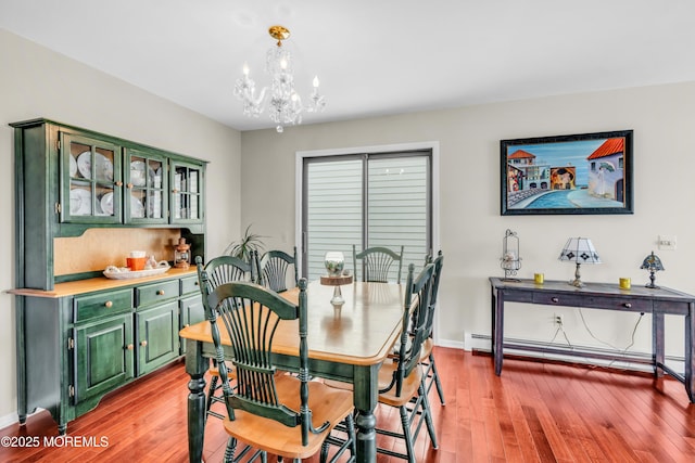 dining room with light wood-type flooring, baseboards, baseboard heating, and an inviting chandelier