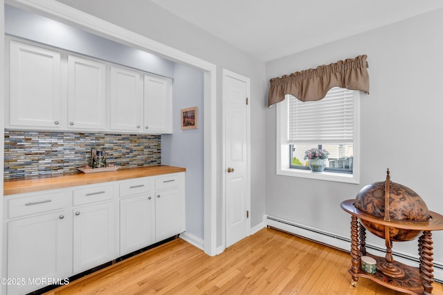 kitchen featuring baseboard heating, backsplash, light wood-type flooring, and butcher block countertops