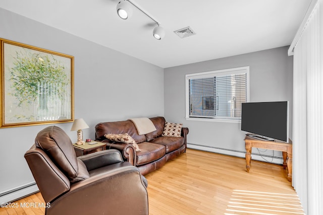 living area featuring a baseboard radiator, light wood finished floors, and visible vents