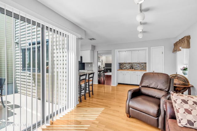living area featuring light wood-type flooring and visible vents