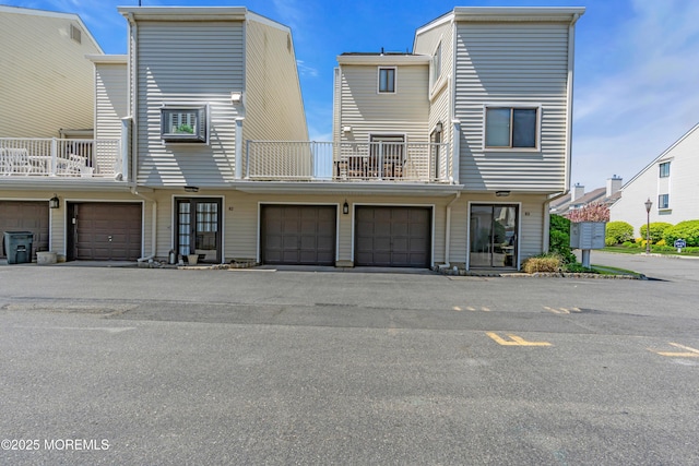 rear view of house featuring an attached garage and a balcony