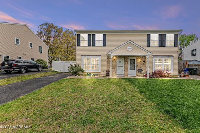 view of front of home featuring brick siding, fence, and a front lawn