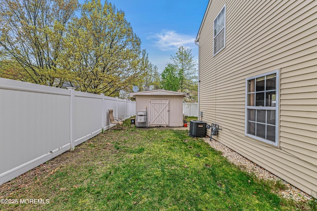 view of yard with a fenced backyard, a storage unit, an outbuilding, and central air condition unit