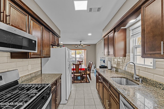 kitchen with a sink, stainless steel appliances, light tile patterned floors, tasteful backsplash, and visible vents