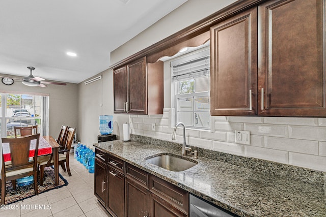 kitchen with ceiling fan, a sink, stone countertops, light tile patterned floors, and tasteful backsplash