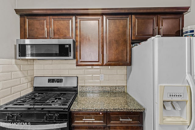 kitchen featuring appliances with stainless steel finishes, tasteful backsplash, dark stone countertops, and dark brown cabinets