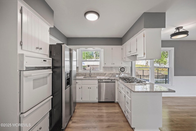 2338 Ramshorn Dr, Allenwood, NJ 08720 - kitchen with a sink, a peninsula, a warming drawer, stainless steel appliances, and light wood-style flooring