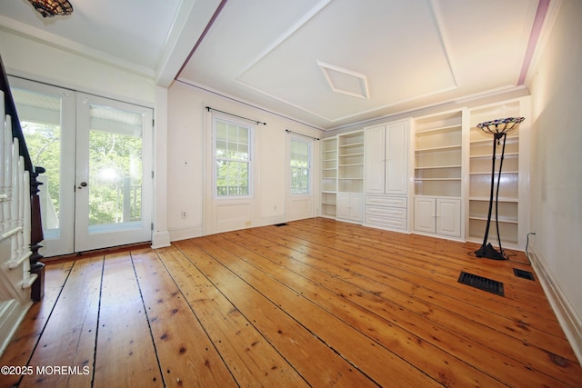 interior space featuring wood-type flooring, ornamental molding, french doors, and built in shelves