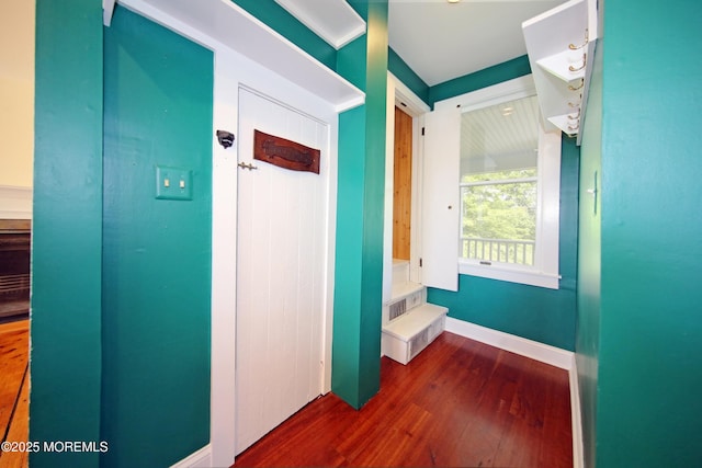 corridor with dark wood-style flooring and baseboards