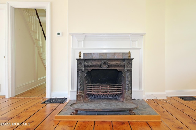 detailed view of wood finished floors, a fireplace, and baseboards