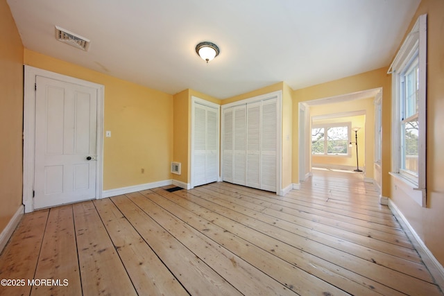 unfurnished bedroom featuring light wood finished floors, baseboards, and a closet