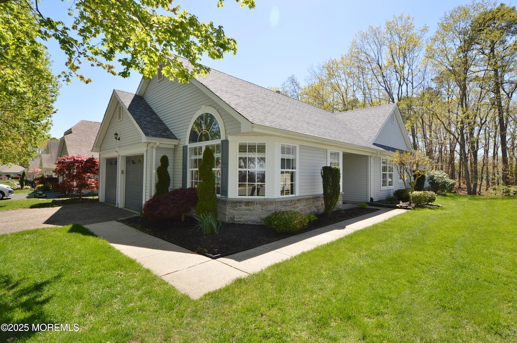 view of side of home with a yard, driveway, and a shingled roof