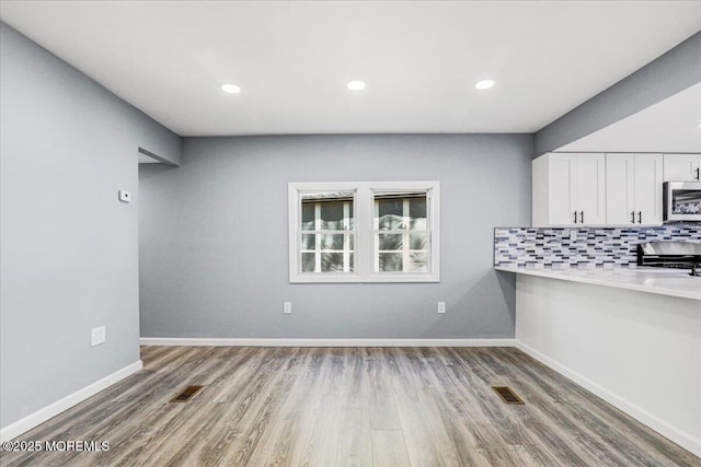 unfurnished living room featuring baseboards, recessed lighting, wood finished floors, and visible vents