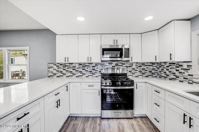 kitchen with appliances with stainless steel finishes, white cabinets, recessed lighting, and light wood-style flooring