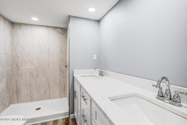 bathroom featuring wood finished floors, a sink, a stall shower, and recessed lighting