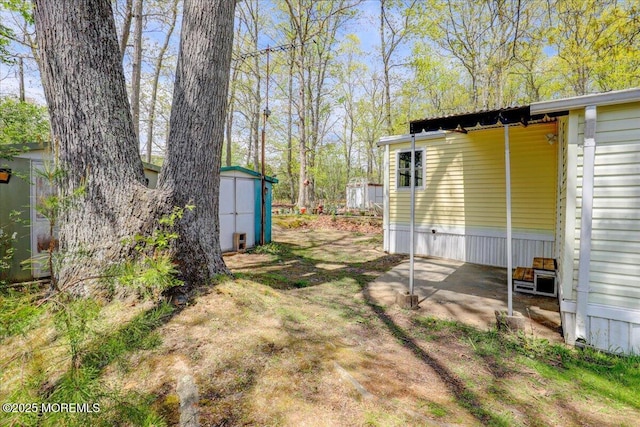 view of yard with an outdoor structure, a storage shed, and a patio