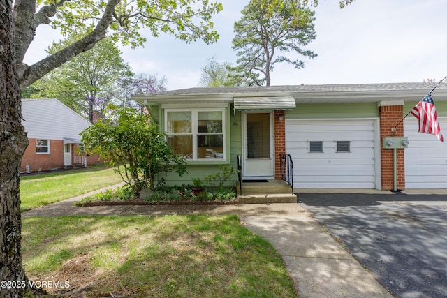 view of front of home with an attached garage, aphalt driveway, a front lawn, and brick siding