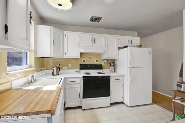 kitchen with freestanding refrigerator, electric range, light floors, under cabinet range hood, and a sink