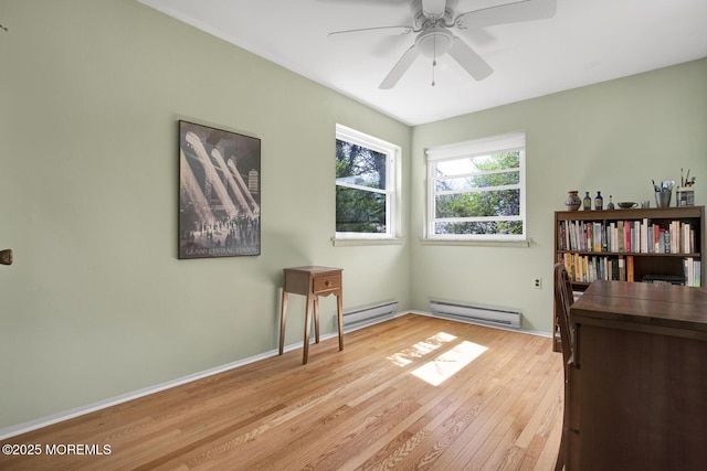interior space with baseboards, baseboard heating, a ceiling fan, and light wood-style flooring