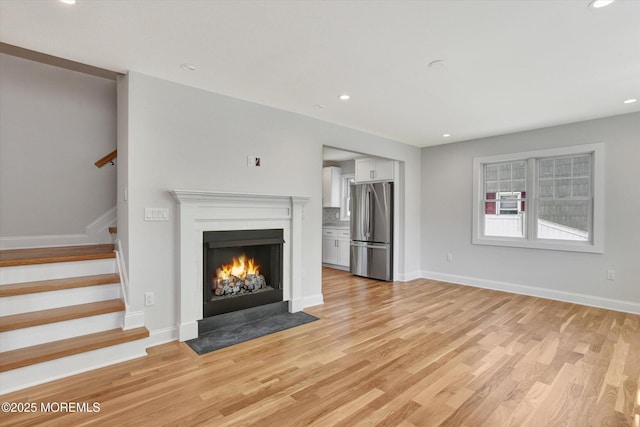 26 Rumson Pl, Little Silver, NJ 07739 - unfurnished living room featuring light wood-type flooring, a fireplace with flush hearth, stairs, and baseboards