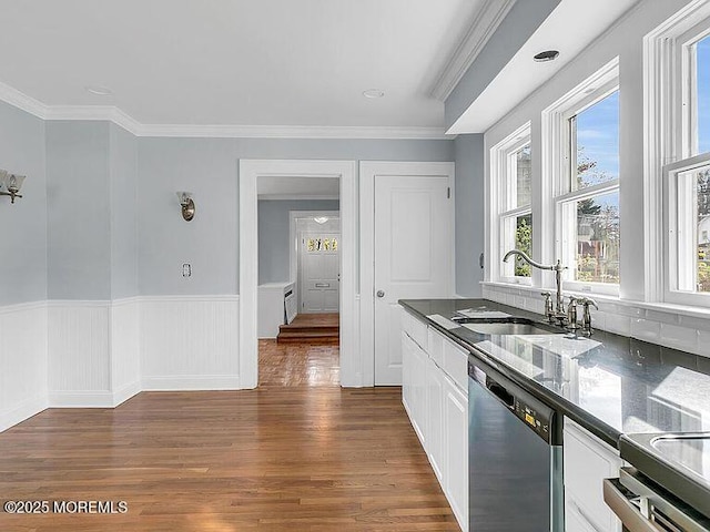 kitchen featuring stainless steel dishwasher, dark countertops, dark wood-type flooring, white cabinets, and a sink