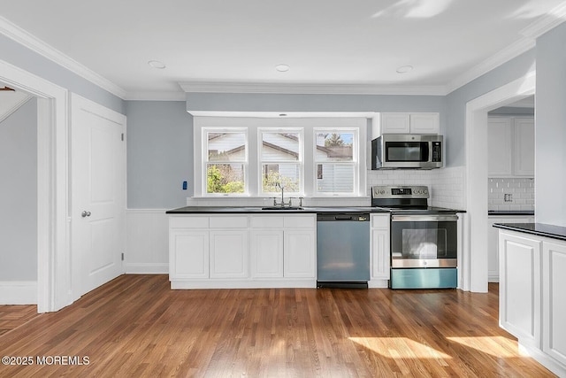kitchen featuring white cabinetry, dark wood-style flooring, dark countertops, and stainless steel appliances