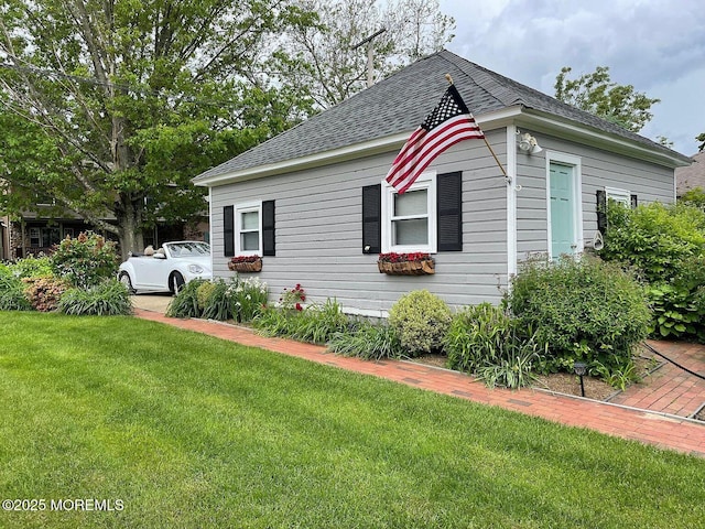 view of side of property featuring roof with shingles and a yard