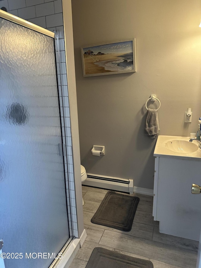 bathroom featuring vanity, toilet, baseboards, a baseboard heating unit, and a shower stall