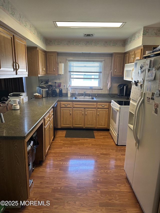 kitchen with visible vents, dark countertops, dark wood-style flooring, and white appliances
