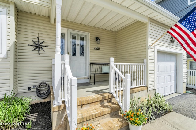 view of exterior entry with a garage and covered porch