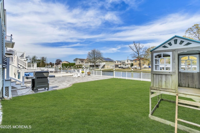 view of yard with a fenced backyard, stairway, a patio area, and a water view