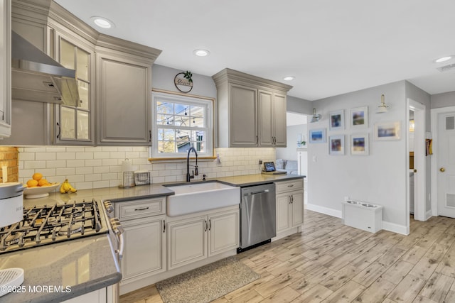 kitchen with baseboards, wall chimney exhaust hood, tasteful backsplash, a sink, and dishwasher