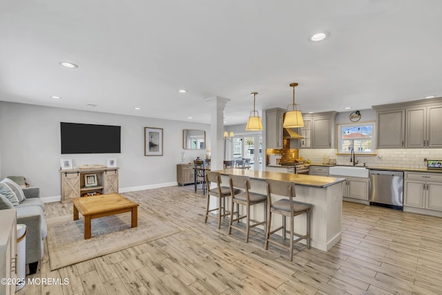 kitchen with decorative backsplash, a kitchen breakfast bar, a sink, open floor plan, and stainless steel appliances