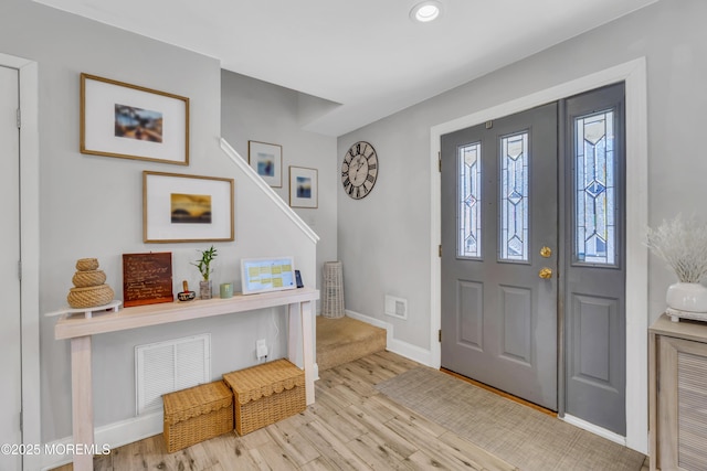 foyer entrance featuring baseboards, wood finished floors, and visible vents