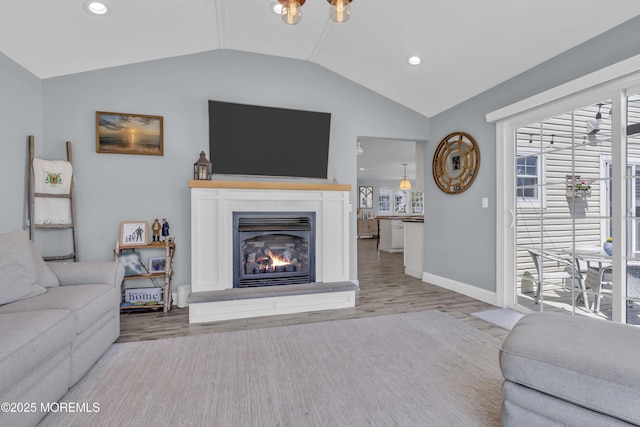 living room with recessed lighting, a glass covered fireplace, wood finished floors, and vaulted ceiling