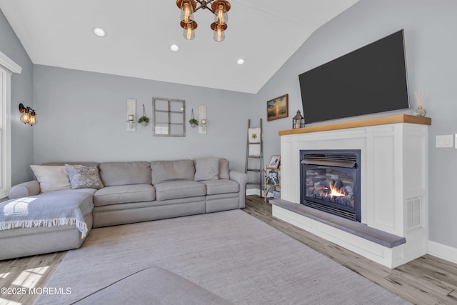 living area featuring a glass covered fireplace, recessed lighting, wood finished floors, lofted ceiling, and visible vents