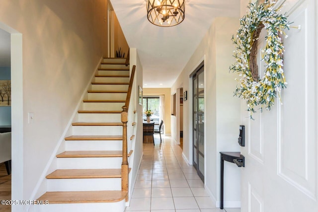foyer entrance with stairs, baseboards, and light tile patterned floors