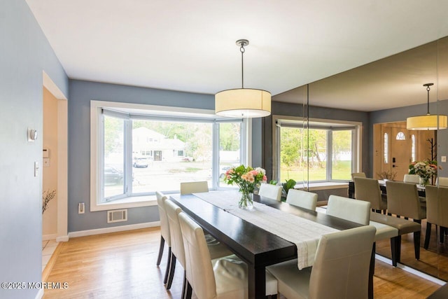 dining space featuring baseboards, light wood-type flooring, and visible vents